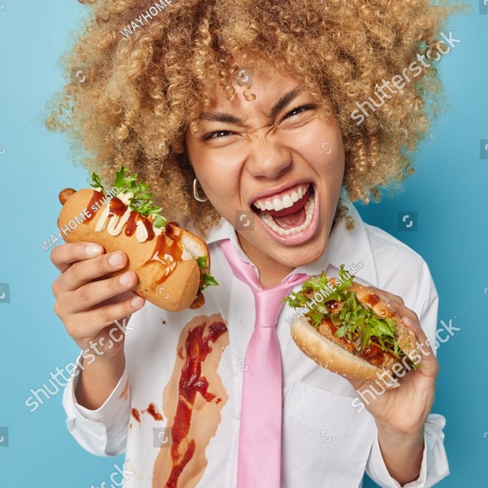 stock-photo-curly-haired-woman-enjoys-eating-cheat-meal-holds-sandwich-and-hot-dog-enjoys-favorite-fast-food-2164128899