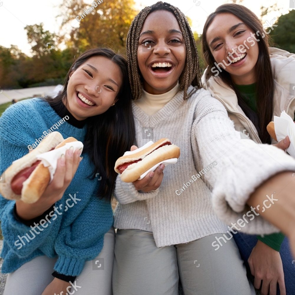 stock-photo-vertical-group-cheerful-girls-selfie-eating-takeaway-street-food-sitting-on-bench-in-nice-area-city-2278760683